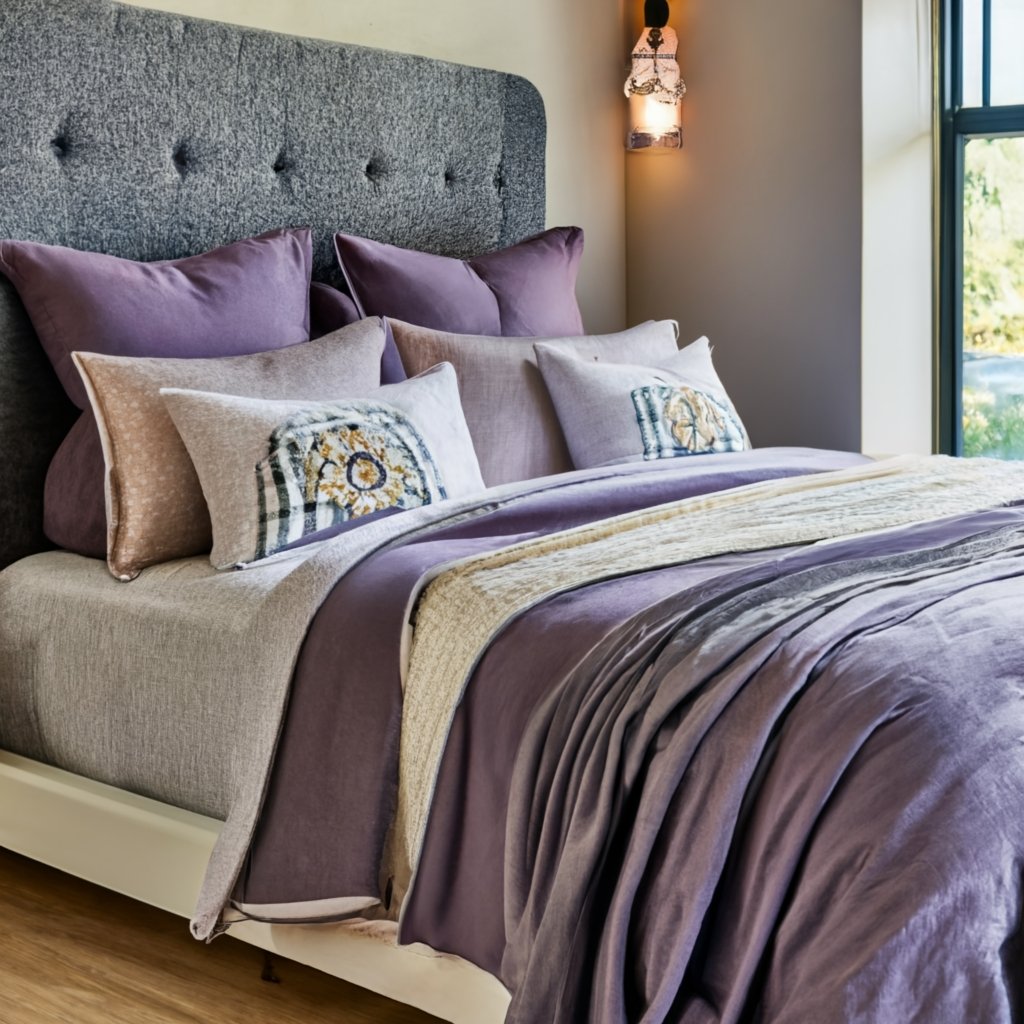 a large bed with purple themed bedding and lavender coloured cushions scattered inspired by the guide on how to How to Use Lavender Every Day 