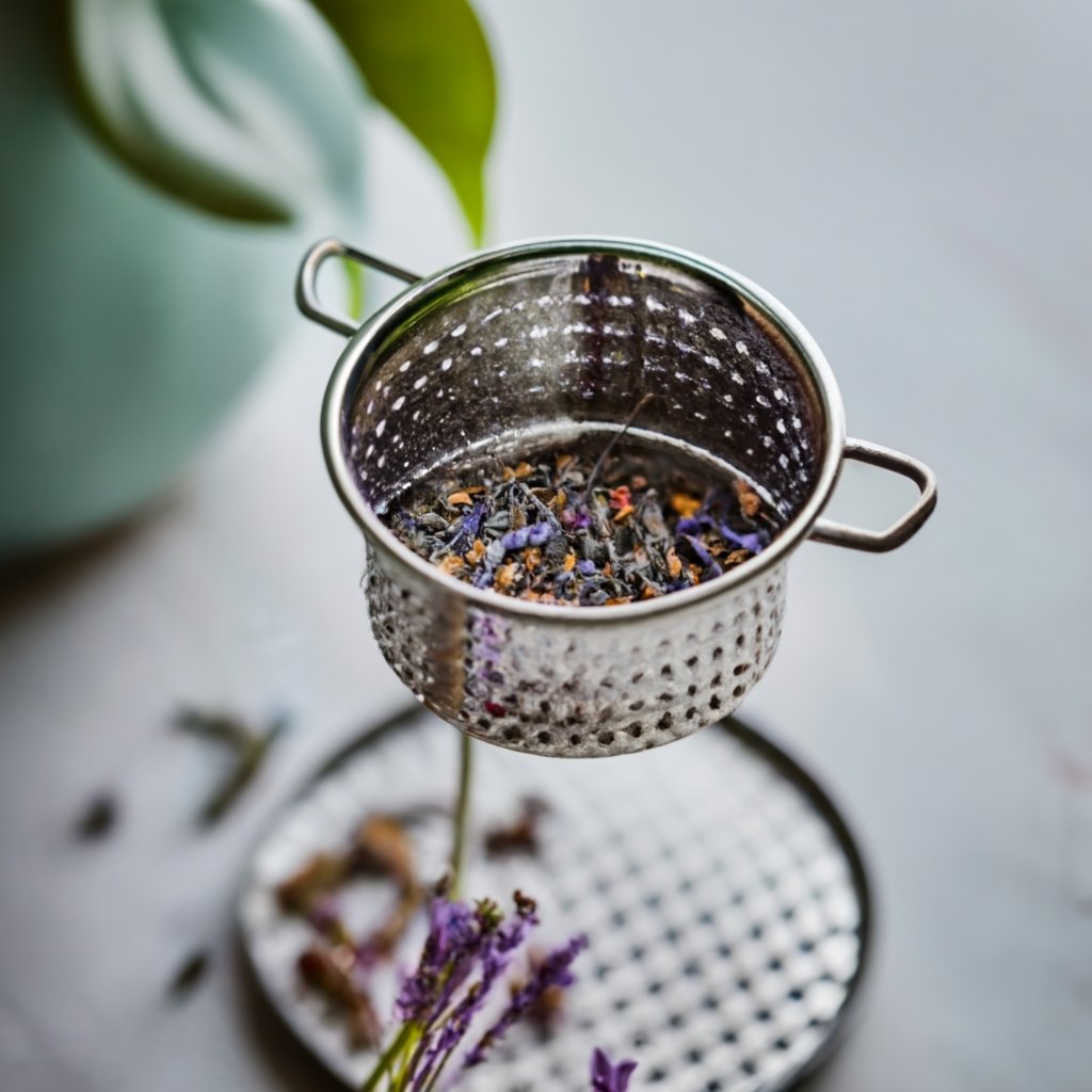 a silver strainer with lavender in it being strained to make tea using one of the Lavender tea recipes.