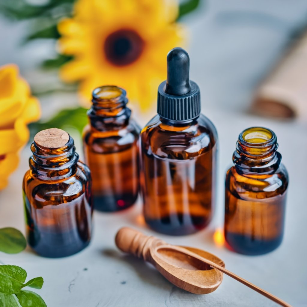 amber glass bottles for essential oils. there are 4 in a row with a sunflower behind them These are useful for storing Lavender Essential Oil 