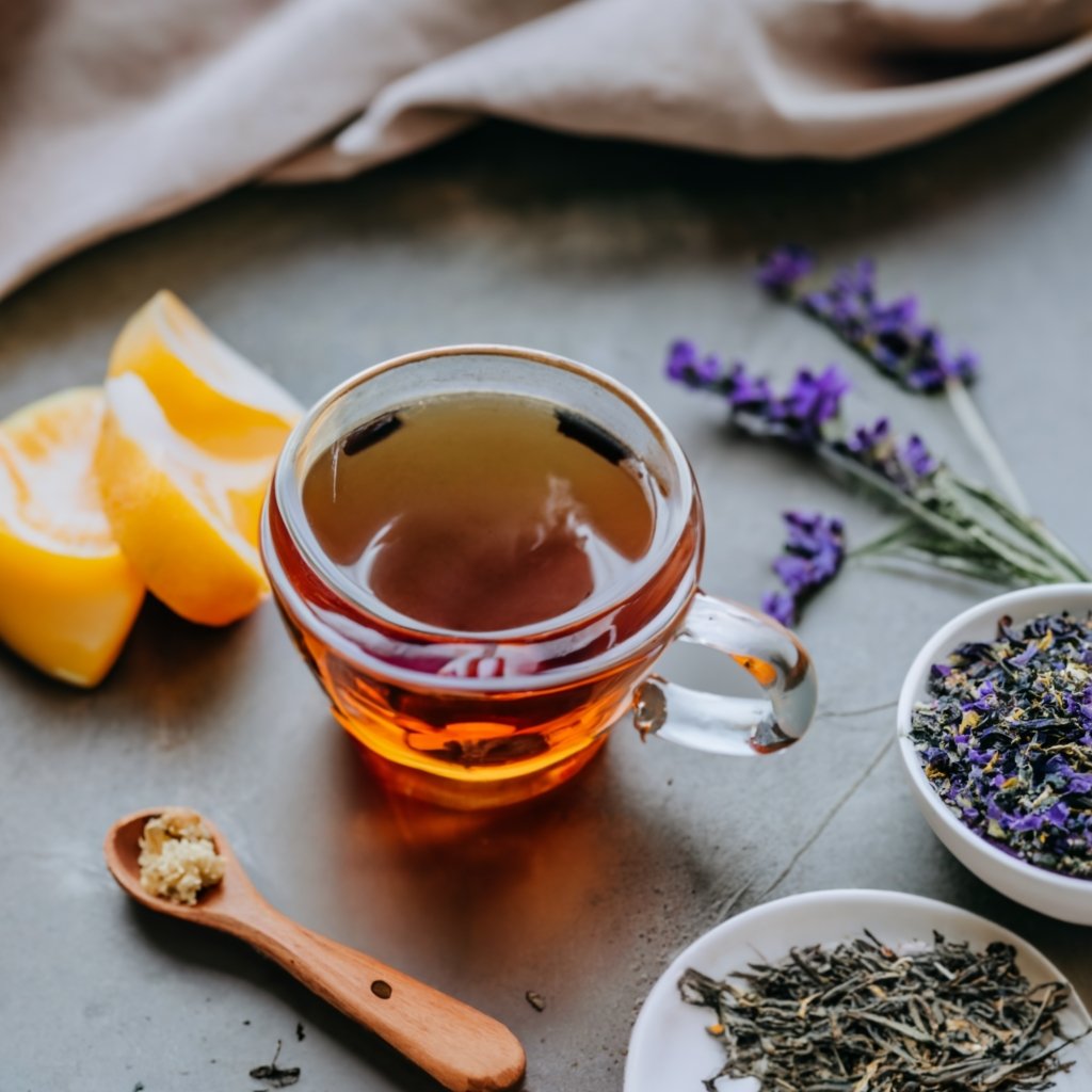 a glass pot of tea infused with lavender on a white table with stems of lavender beside the glass Inspired by the guide on how to Learn how to cook with Lavender 